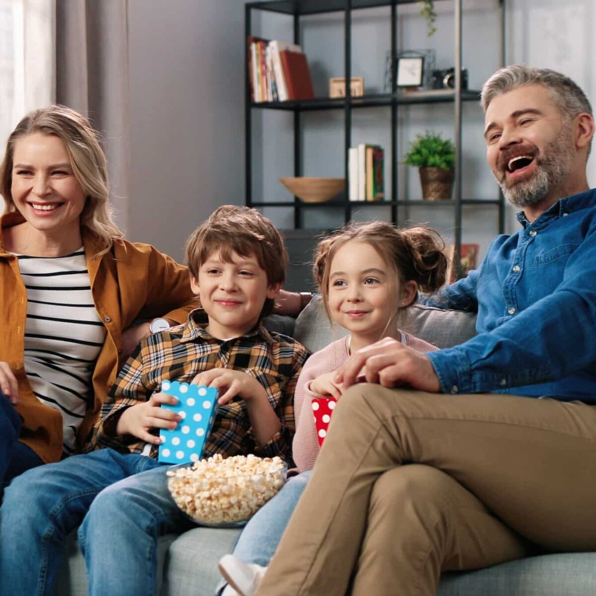 Eine Familie mit zwei Kindern schaut gemeinsam Serien auf dem Fernseher zu Hause.