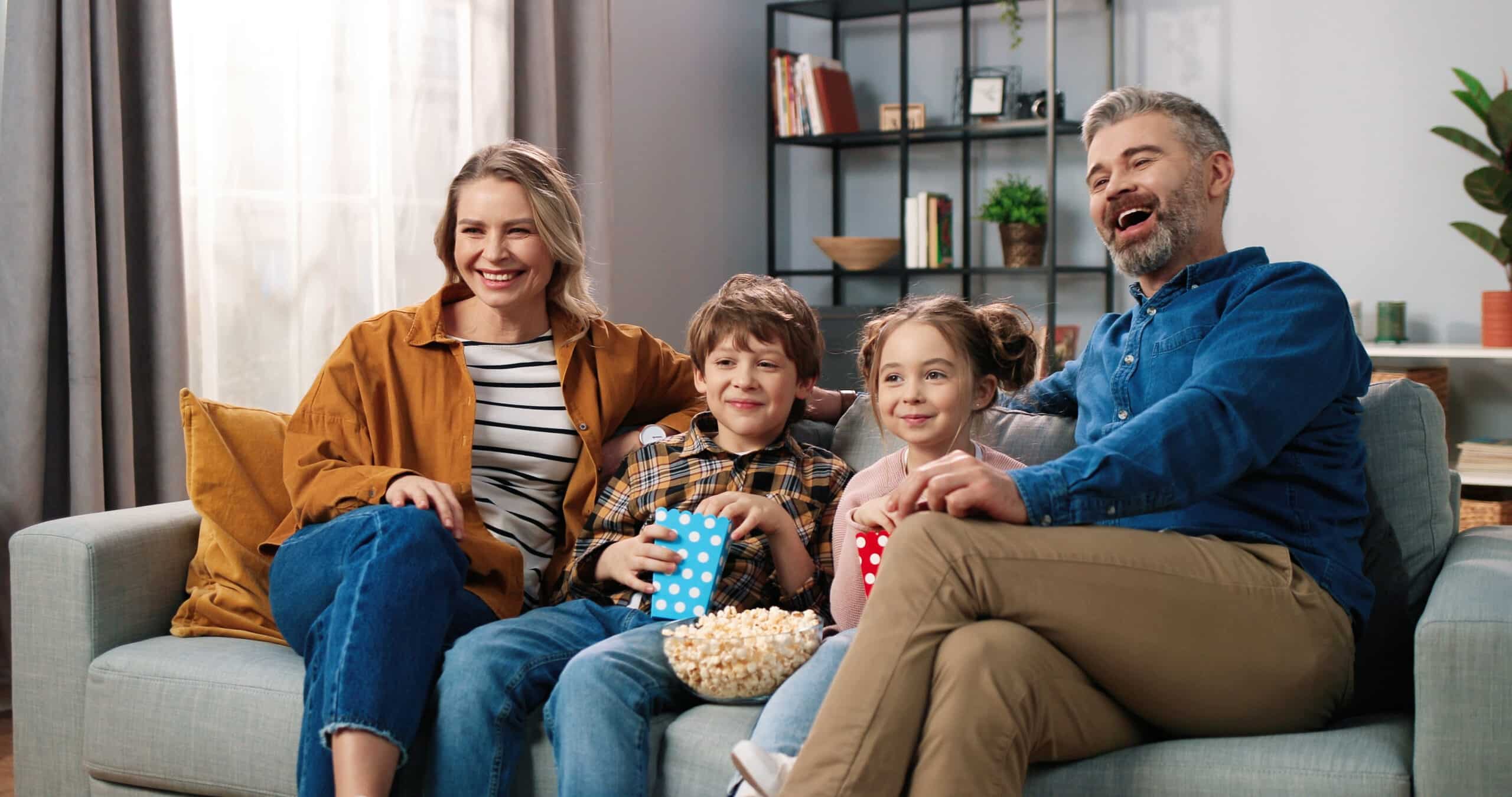 Eine Familie mit zwei Kindern schaut gemeinsam Serien auf dem Fernseher zu Hause.