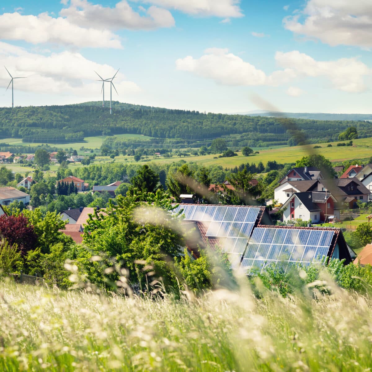 Ein Bild einer Gemeinde mit Häuser im Hintergrund, welche Photovoltaikanlagen auf dem Dach haben.