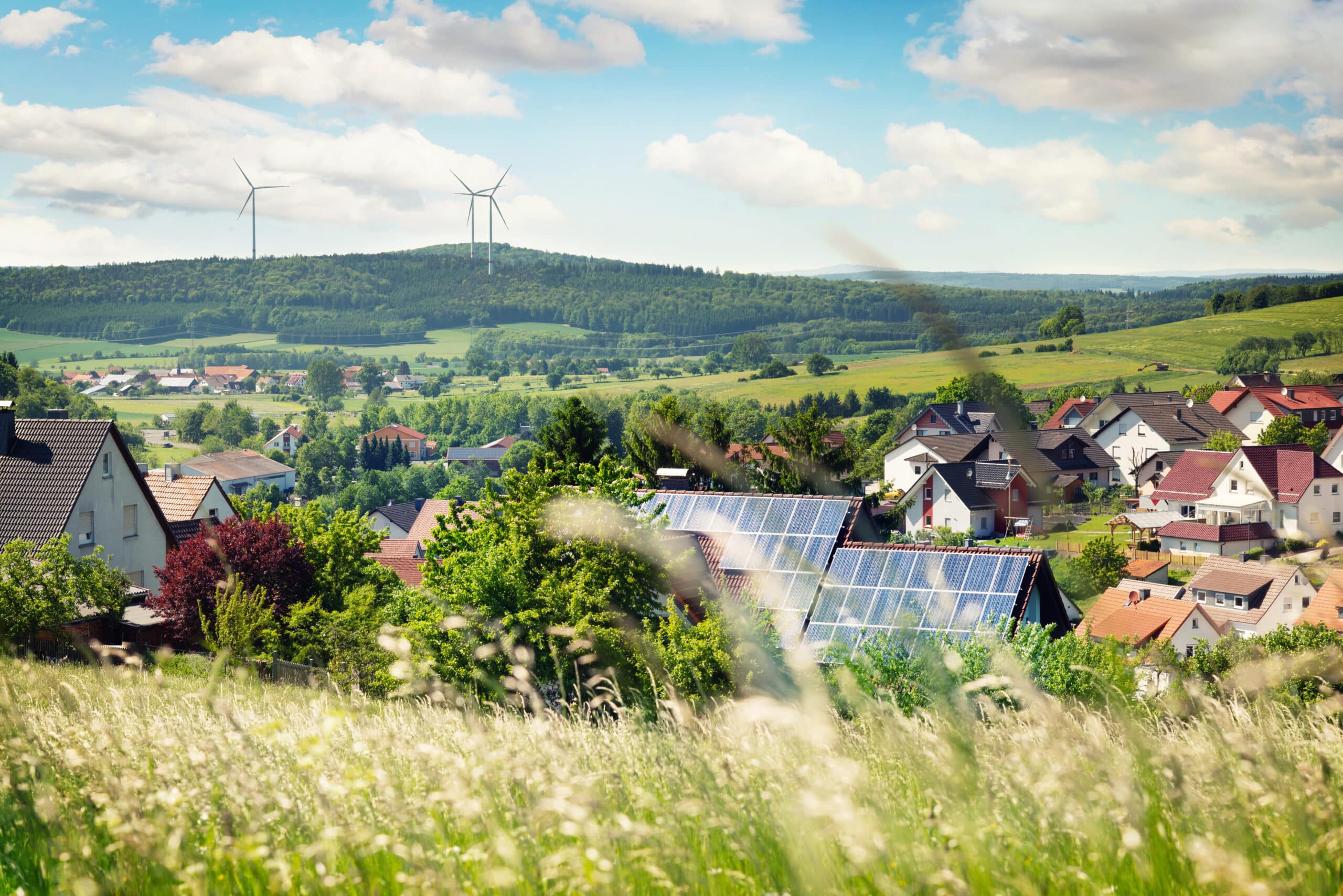 Ein Bild einer Gemeinde mit Häuser im Hintergrund, welche Photovoltaikanlagen auf dem Dach haben.